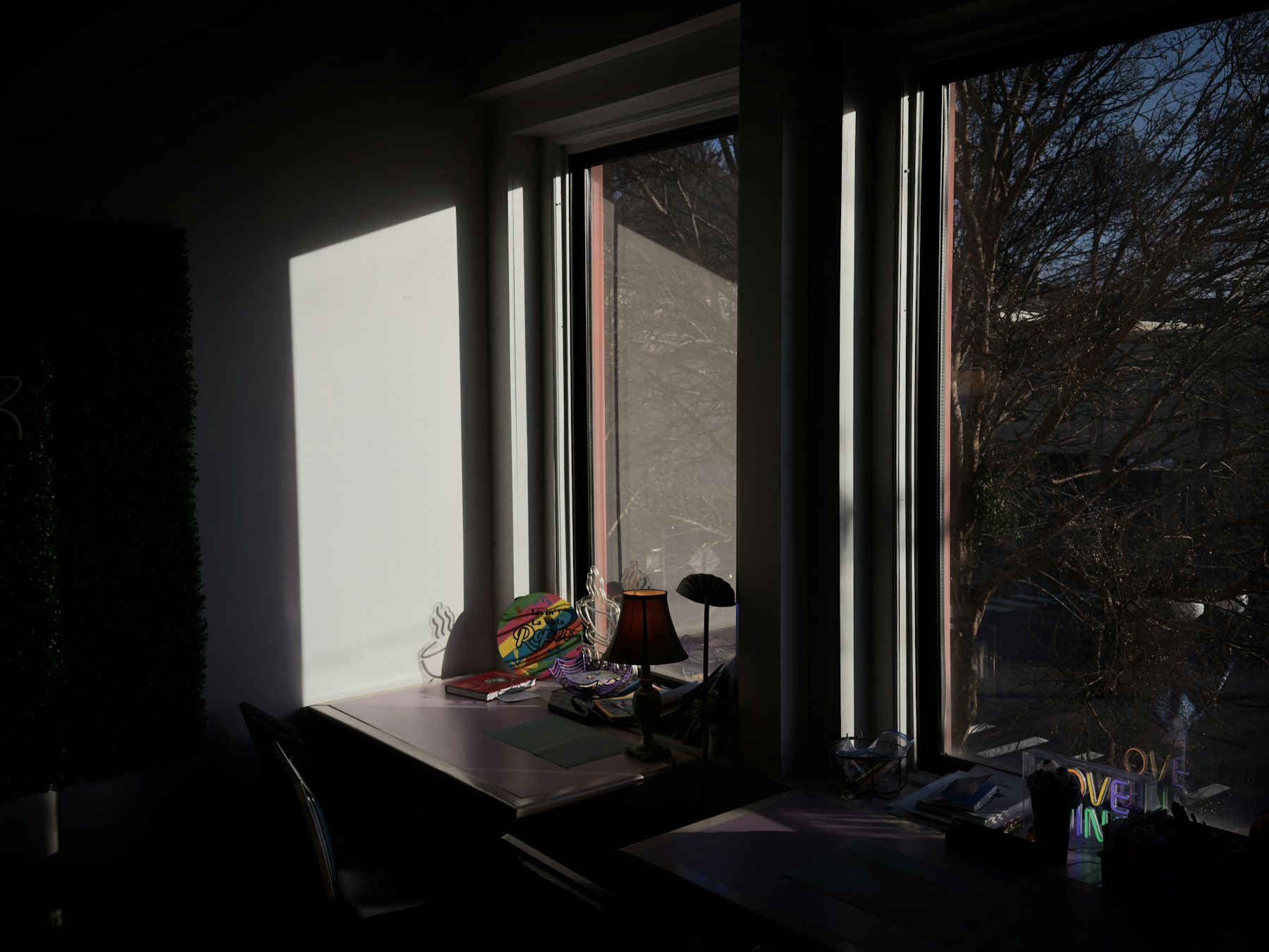 A quiet desk beside a bright window, seen from the shaded side of the room