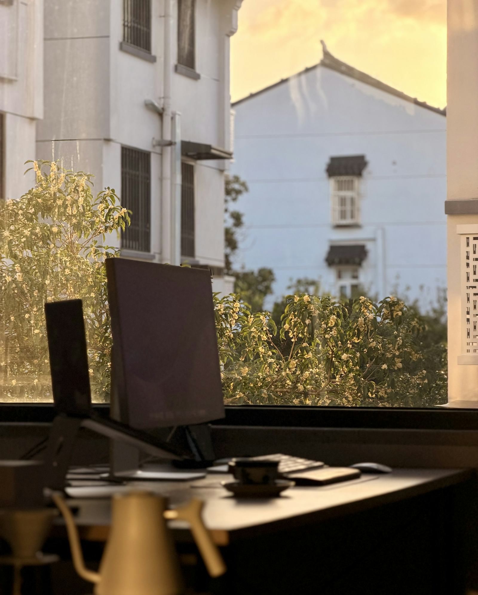A laptop on a desk at a window in warm evening light