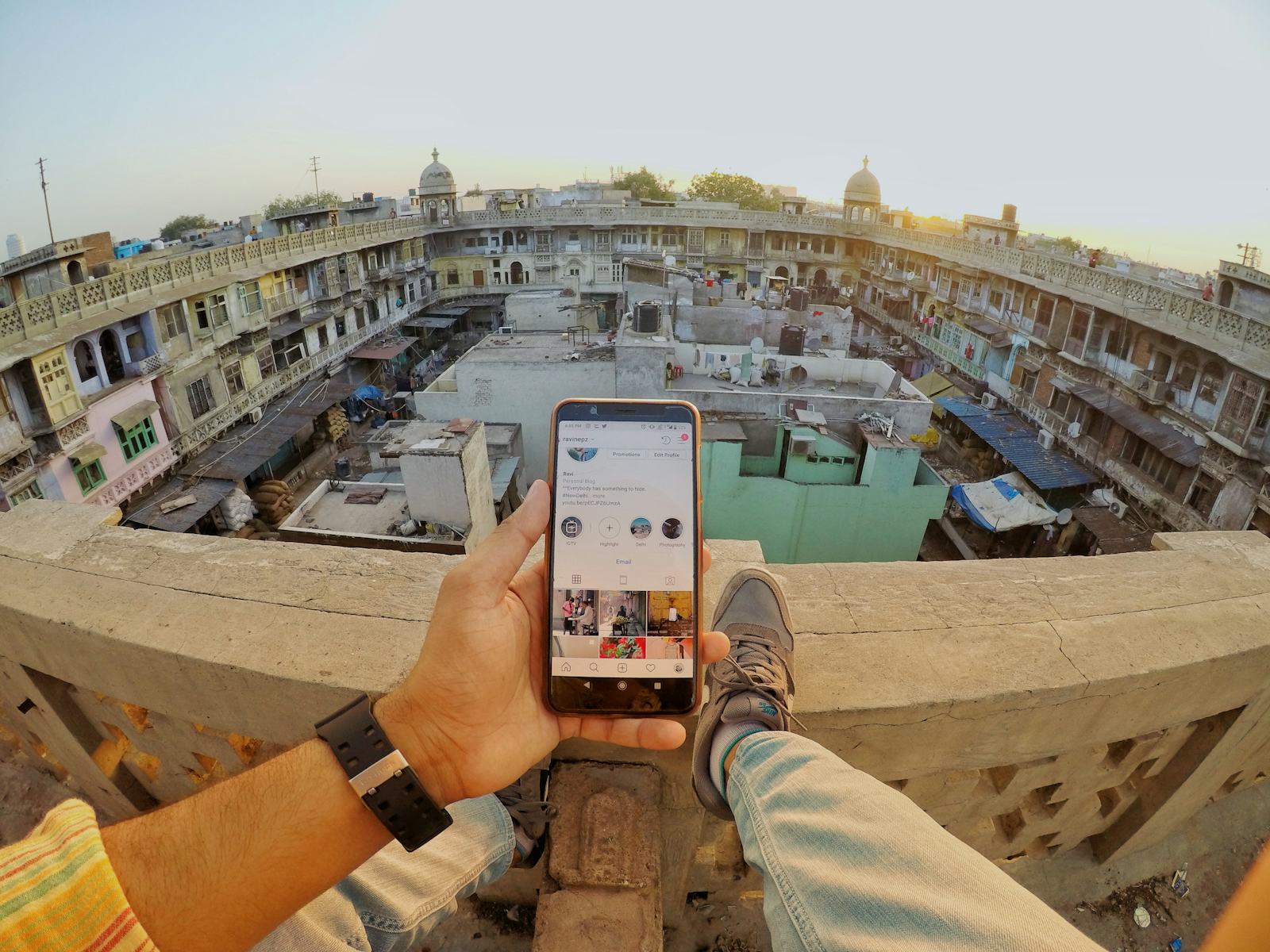 A phone held up over a rooftop view of an Indian town
